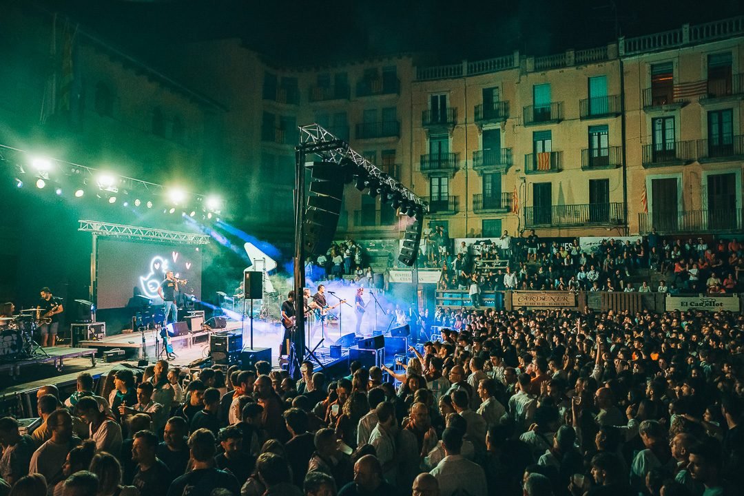 Concert en una plaça plena de gent amb els balcons al fons
