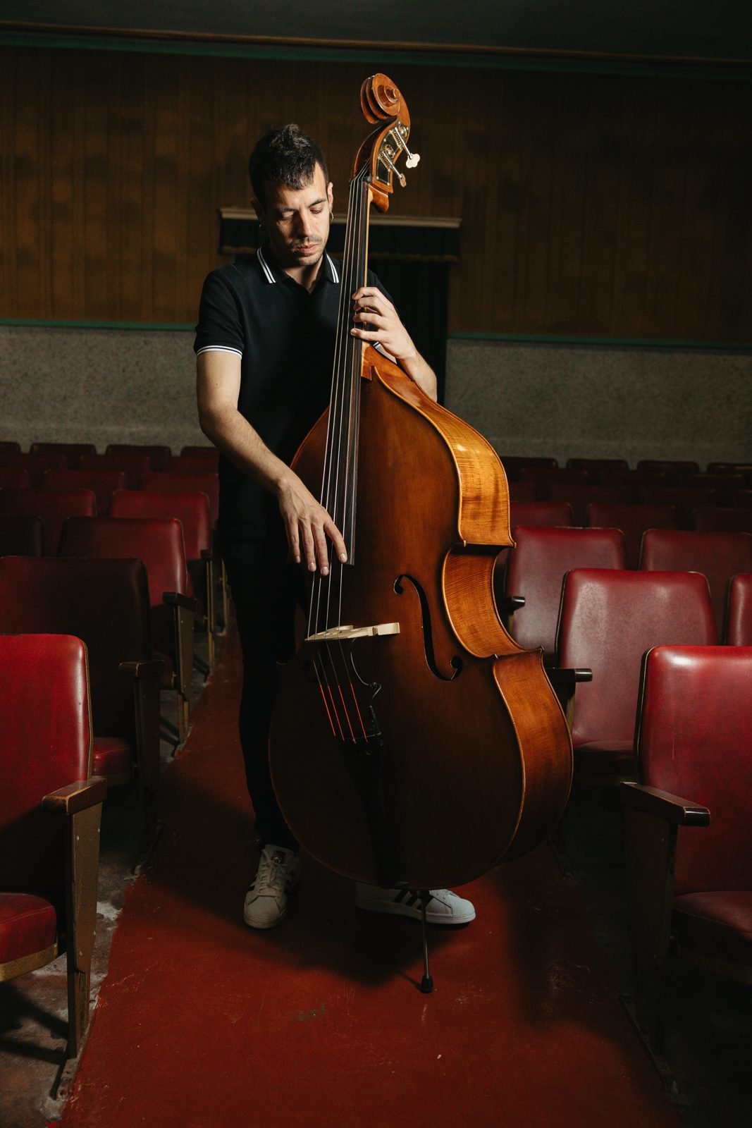 Retrat d'un músic amb el contrabaix al passadís d'un teatre