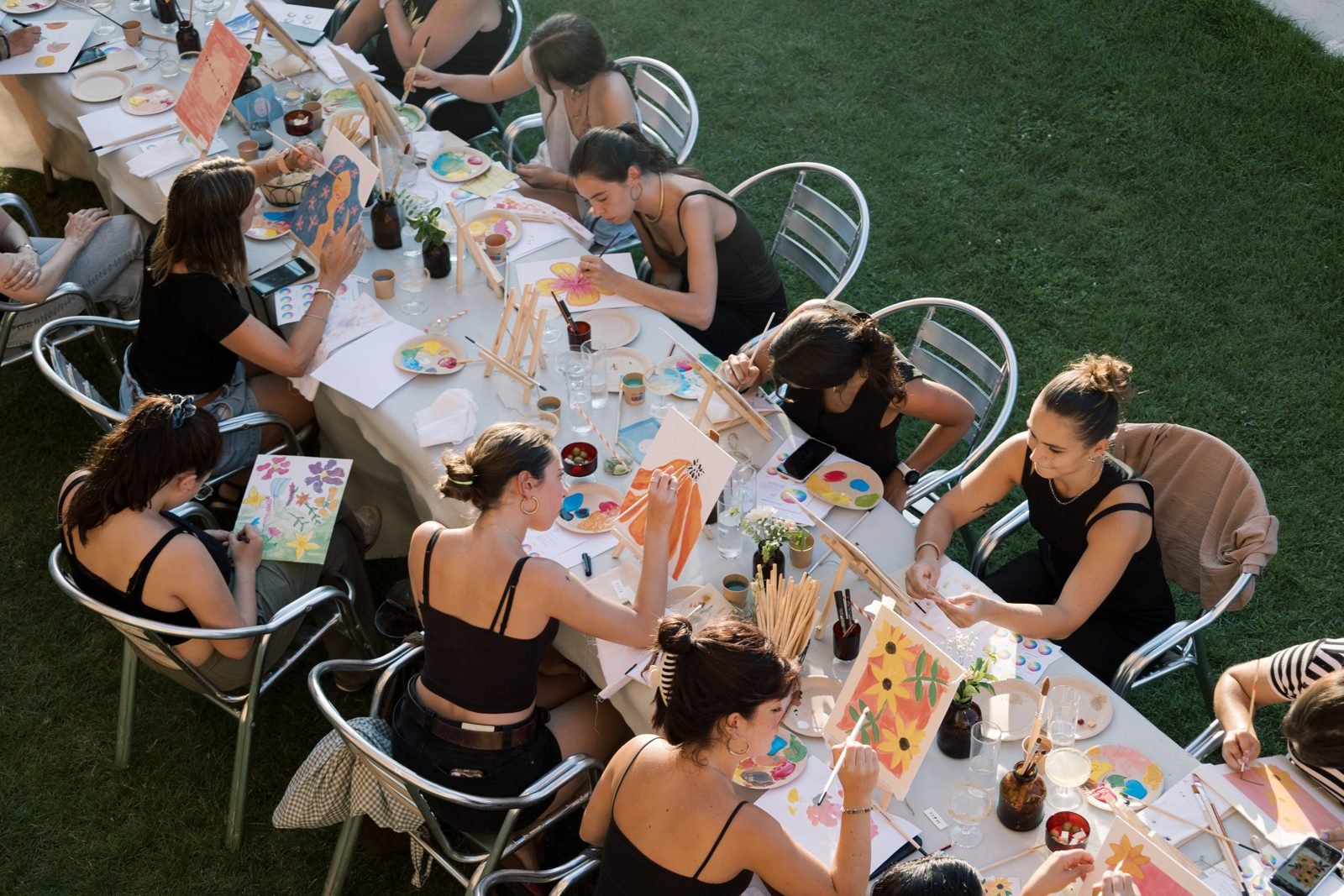 Taller de pintura a l'aire lliure: participants pintant al voltant d'una taula llarga