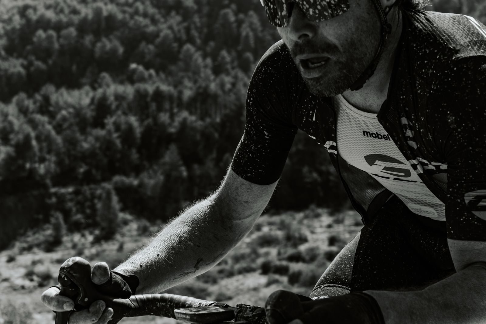 Ciclista en plena cursa amb el bosc al fons, en blanc i negre