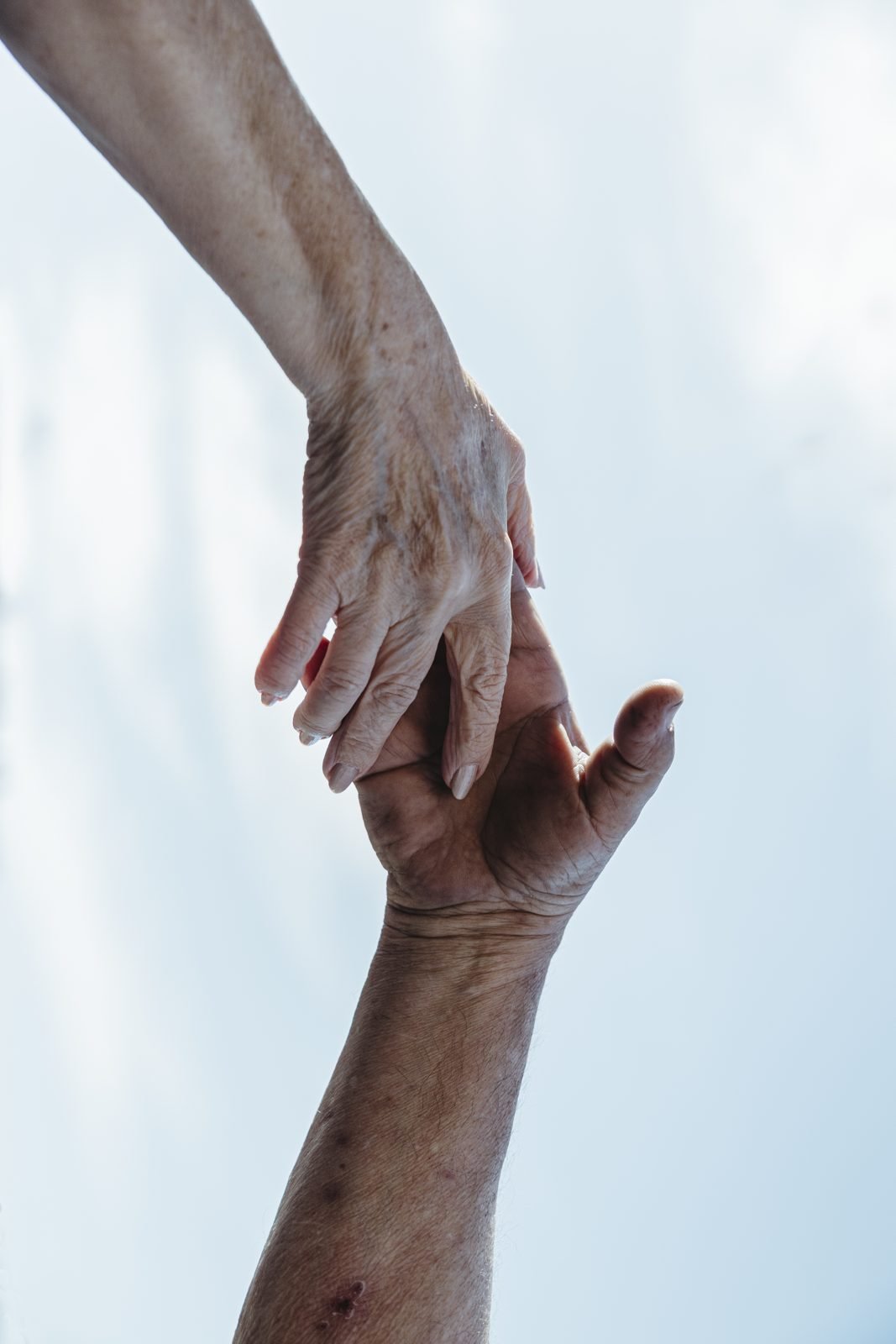 Les mans de dues persones grans agafant-se contra el cel